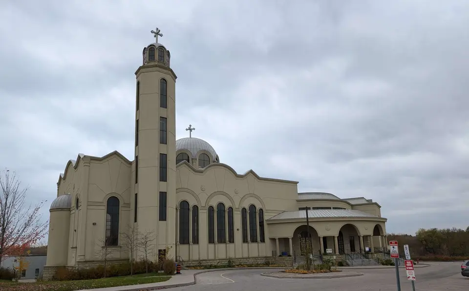 A wide view of the cream church, bell tower, and silver dome from the drive