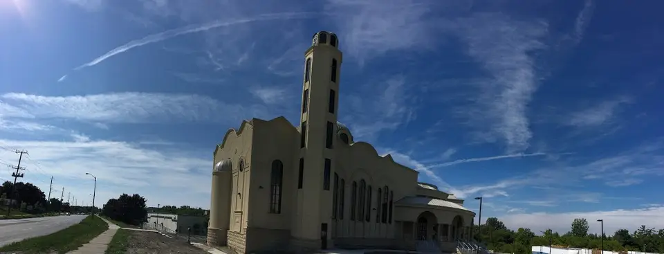 A low wide view of the stone church and bell tower along Westney Road